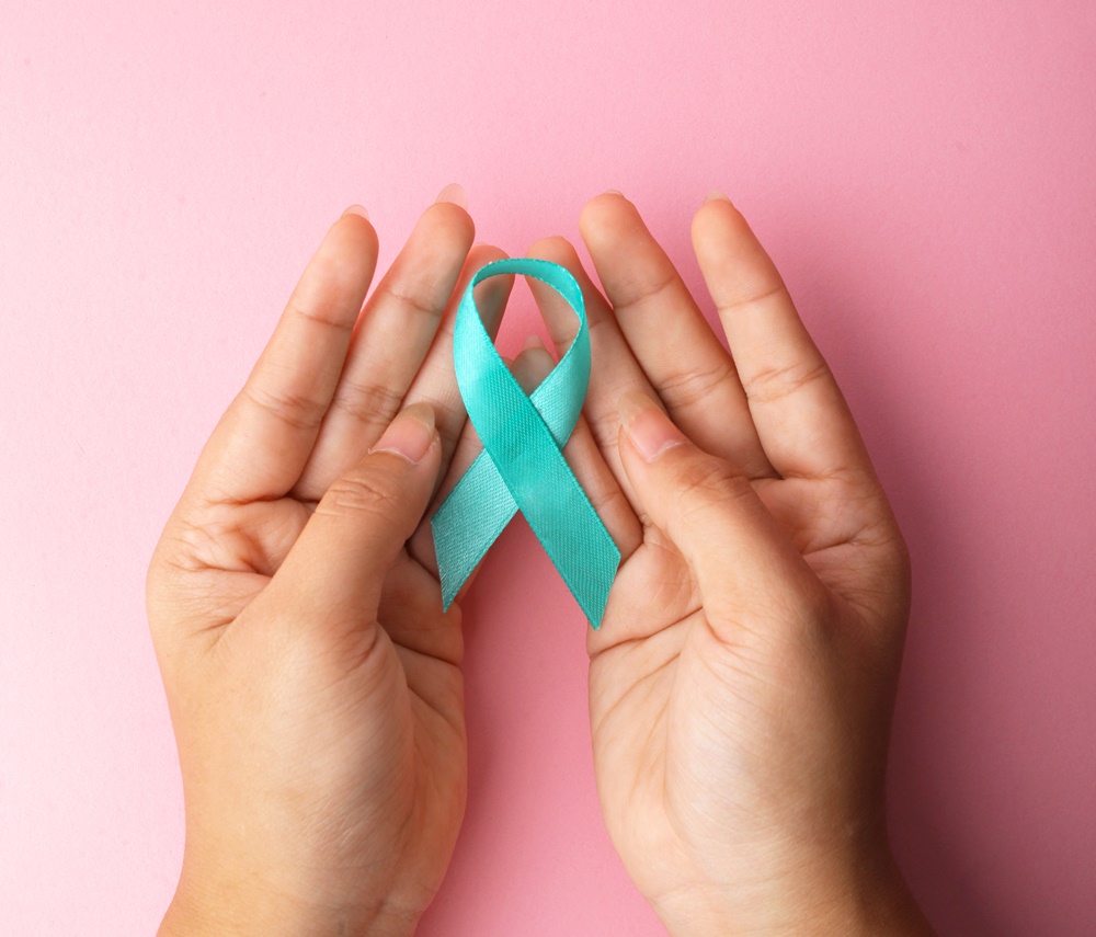 Hand Holding Teal Ribbon On Pink Background Support Ovarian And Cervical Cancer.