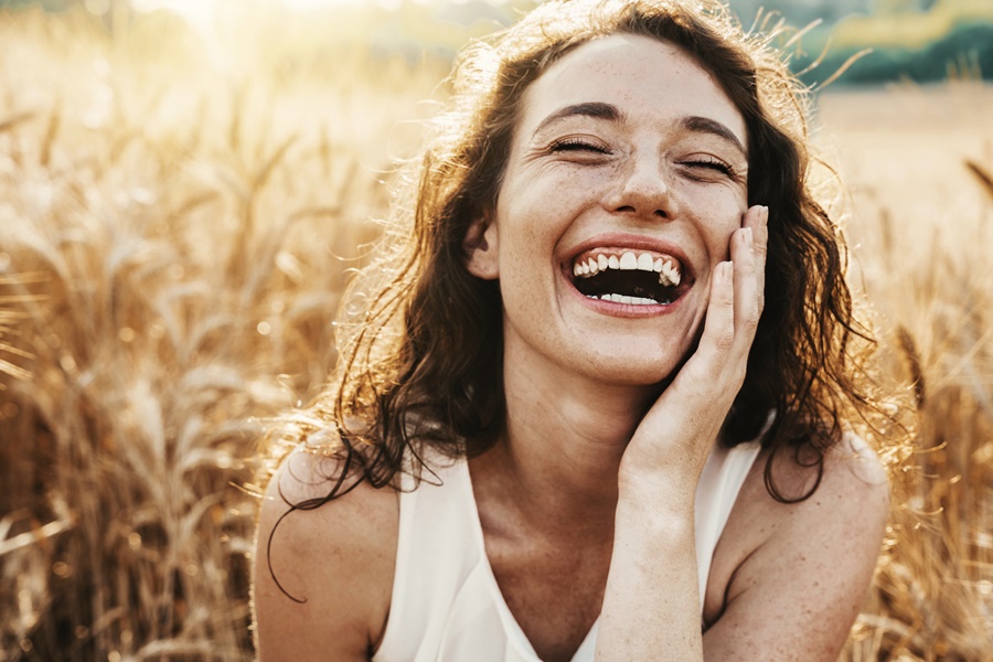 Happy beautiful woman smiling at camera in a wheat field - Delig